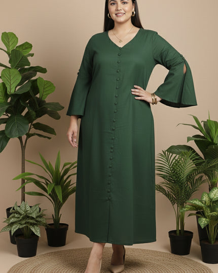Woman wearing a green dress standing in front of potted plants on a beige background